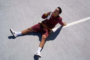 Man drinking water sitting on a sports court. 