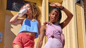 Two women in atheltic clothing drinking Owala water bottles.